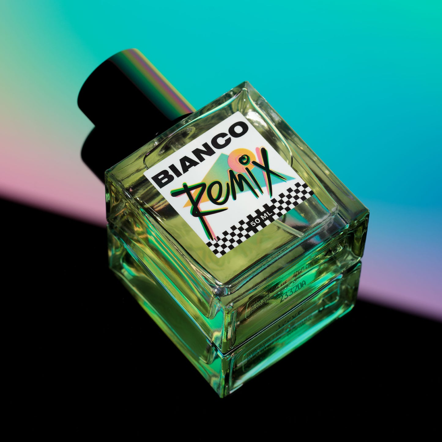 Bianco Profumo remix featuring notes of Vert de Bergamot Italy Orpur™, Vert de Mandarin Italy Orpur™, Lime Oil Ozone, Jasmine, Spearmint, Watery Melon Oakmoss, Amber, and Musk. Bottle laying down on a mirrored surface with a multicolored background. Aquatic citrus style fragrance.